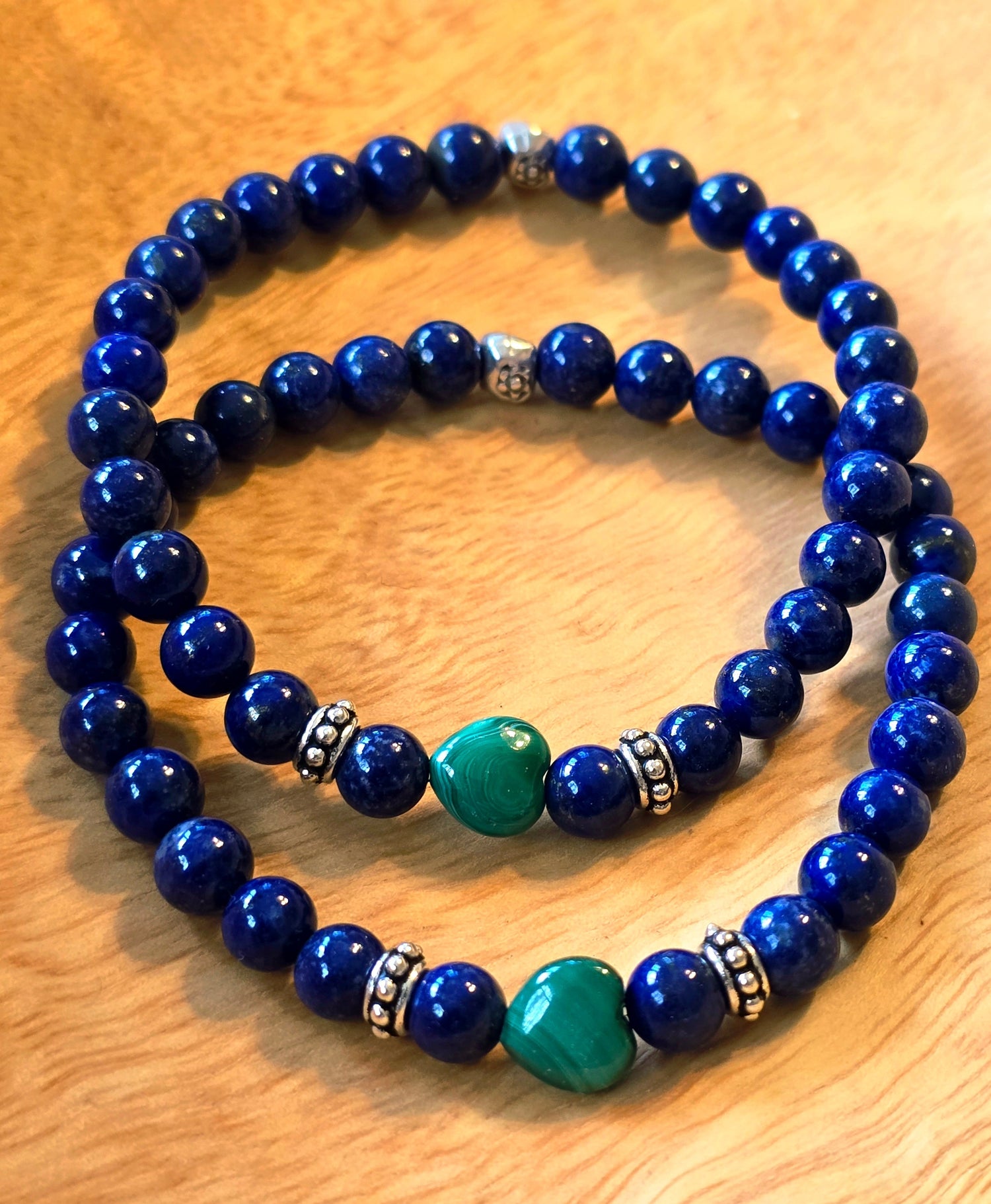 Handmade gemstone bracelets with natural blue stones and green accent beads on wood