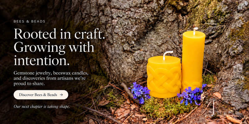 Bees & Beads. Rooted in craft. Growing with intention. Gemstone jewelry, beeswax candles, and discoveries from artisans we’re proud to share. Discover Bees & Beads. Our next chapter is taking shape. Two golden Celtic candles with purple flowers against tree bark.