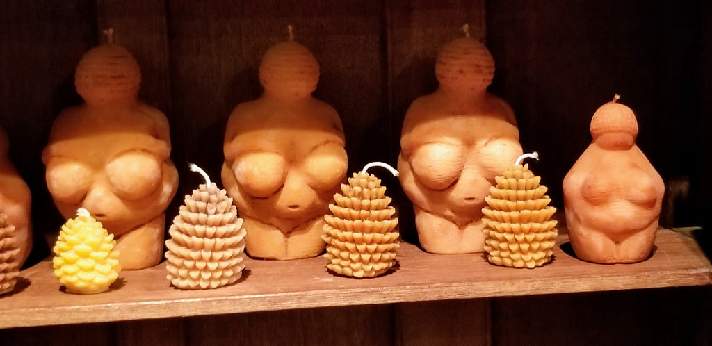 Venus of Willendorf and small pinecone beeswax candles on a rustic wooden shelf